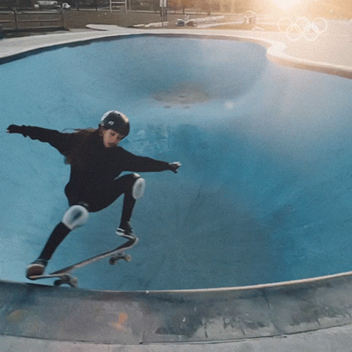 a young man in a helmet is skateboarding at a skate park
