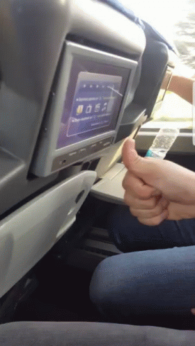 a young person in an airplane seats holding onto a remote control