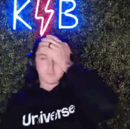 a man with a black shirt has a neon klbb in front of him