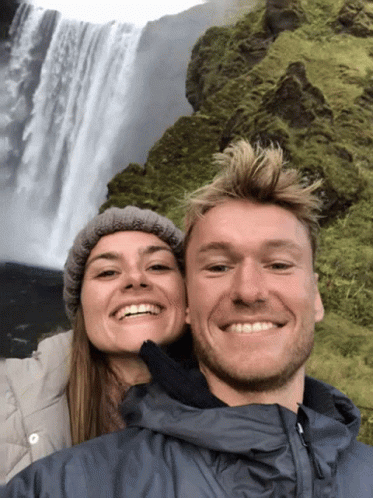 two people stand in front of a waterfall