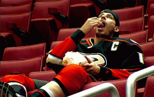 a young male in a jersey is laying down in a seat eating soing out of his mouth