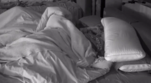 a person covered up in a sheet with pillows