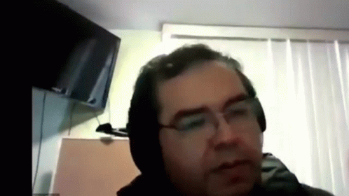 a man in black jacket and glasses taking a video