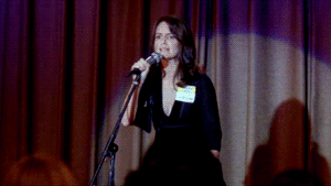 a woman standing on a stage in front of a microphone