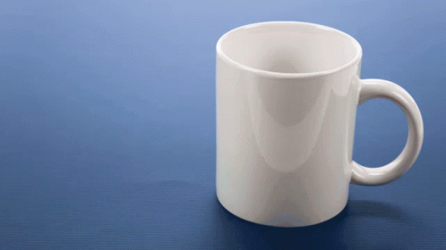 a white mug sits on a shiny brown table