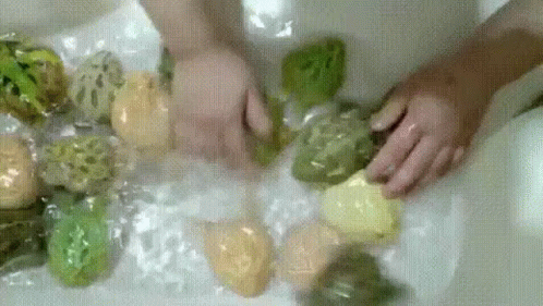 someone with gloves is cleaning some rocks in a tub