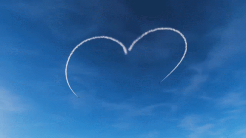 airplane in the sky with heart shaped tail and smoke trails