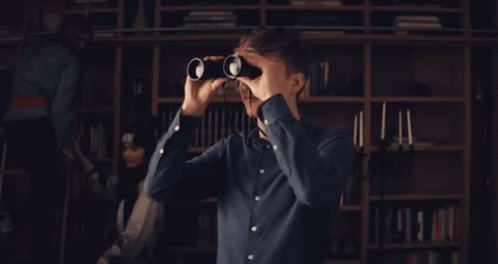 man looking through binoculars in a dark room