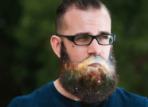a bearded man in a yellow shirt wearing glasses with a galaxy beard