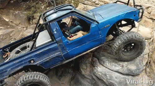 an open jeep with a big tire is on the rocks