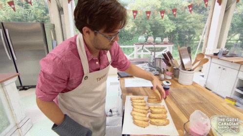 man in blue apron decorating donuts on blue table