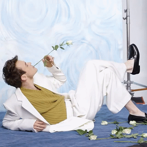 a person laying on a floor holding a flower