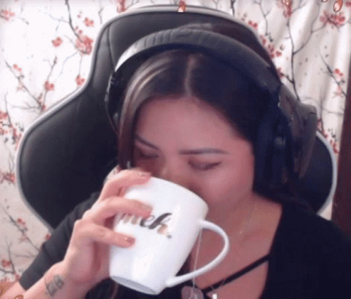 a woman is drinking from a mug and listening to headphones