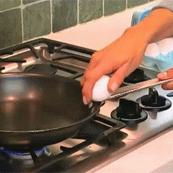 someone cleaning a black pan on the stove