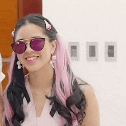 a women with pink hair and sunglasses is smiling