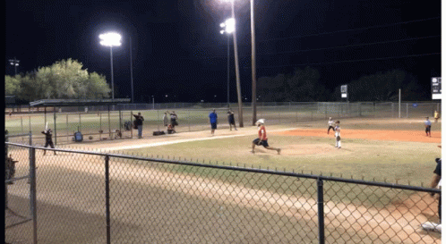 people standing on a baseball field at night with people standing on the field