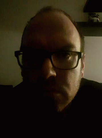 a man wearing black glasses, staring at the camera