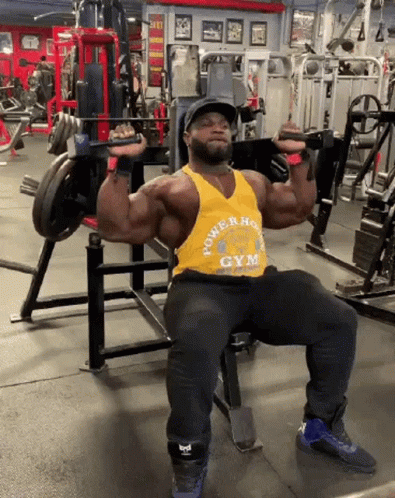a man squats in the middle of a gym while lifting some heavy barbells