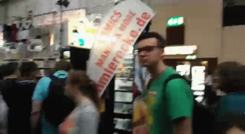 a man holding a sign while wearing a green shirt
