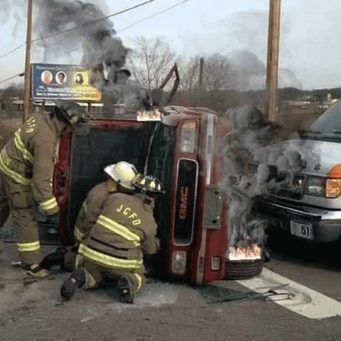 two firemen standing next to the back of a fire truck