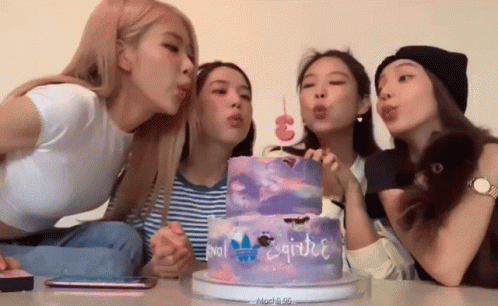 four girls with hats sit near a cake