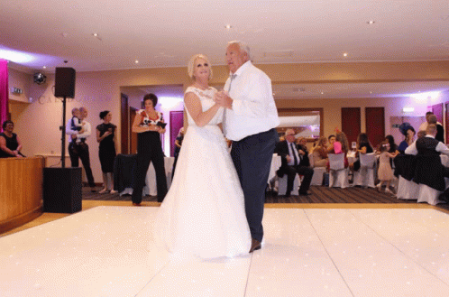 a couple in wedding clothes dance on a dance floor with other people