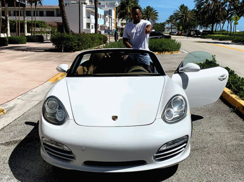 a white sports car with a man standing next to it