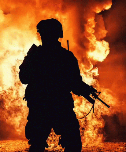 an armed man standing in front of flames