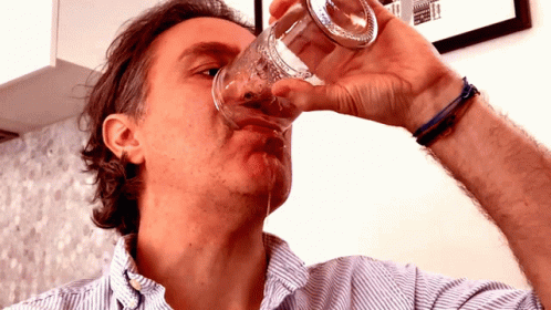 a man is drinking water out of his glass