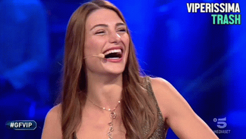 a woman with long brown hair laughing at someone on tv