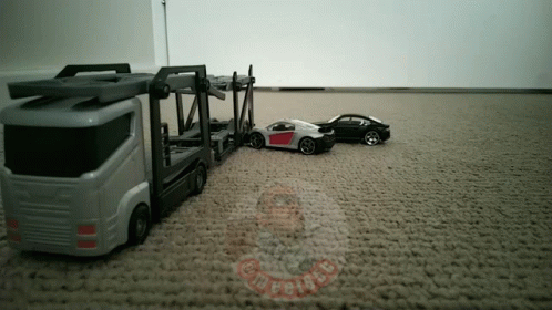 a toy truck with a car sitting on the ground
