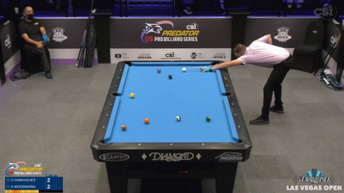 a person leaning over a pool table and aiming at a ball