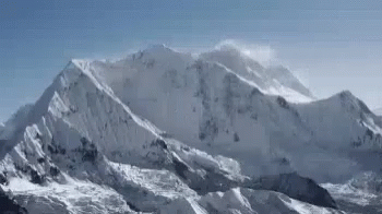 a huge mountain with snow capped mountains in the background
