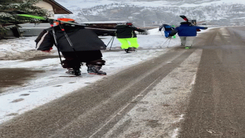 skiers carrying ski poles and ski poles down a snowy road