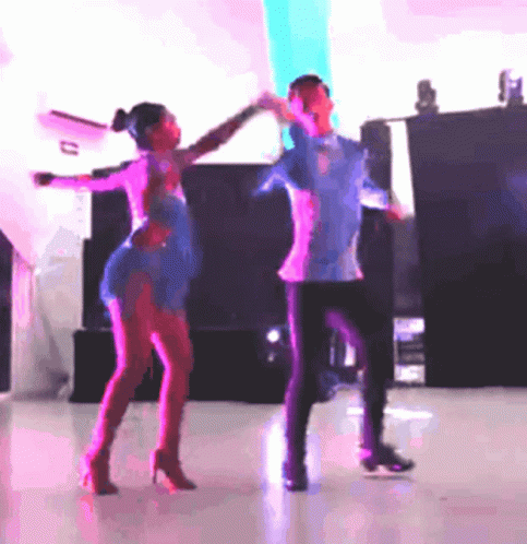 two young adults dance in front of a projector