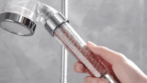 a hand holding an electronic device while using a showerhead