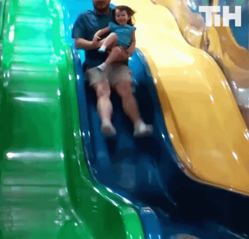 two people playing in a plastic slide in a play yard