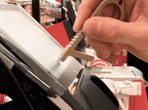 a hand holding a silver tool in front of a machine