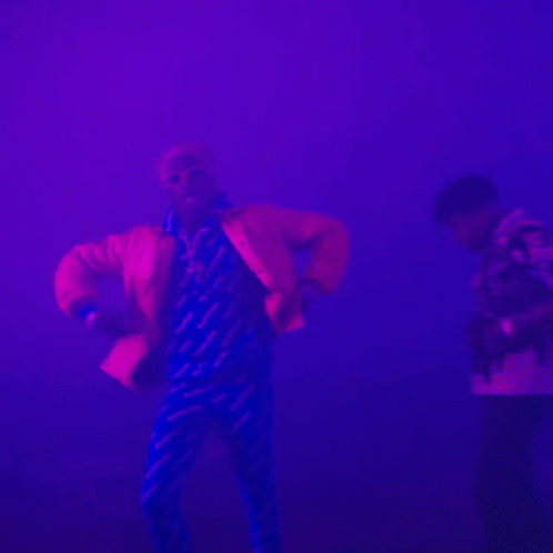 two young men are dancing in a pink, red and white smoke filled area