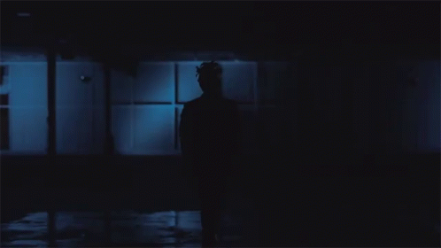 a silhouette of a man standing in a room at night