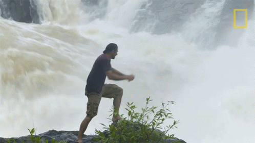 a man that is standing in front of a waterfall