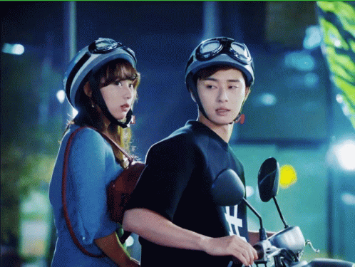 an asian couple on motor bikes at night