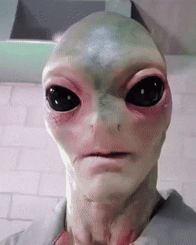 an alien man with big eyes in front of a computer screen
