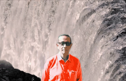 a man standing by the side of a waterfall