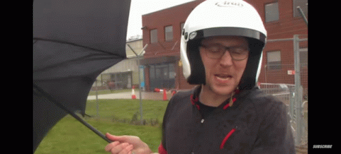 a man wearing glasses and a helmet holding an open umbrella