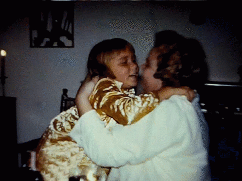 two young children are hugging in a darkened room