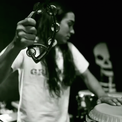 a man with long hair is playing drums