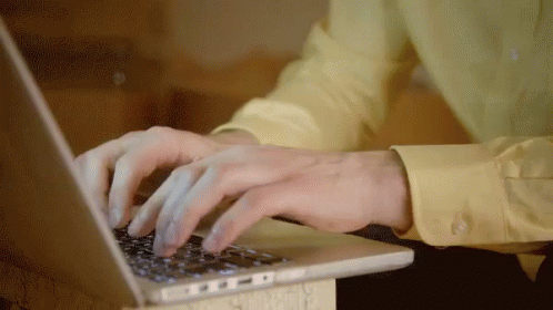 a person wearing gloves typing on a laptop