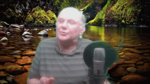 a man standing in front of water with a microphone