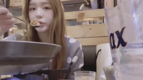 a girl eats food inside a restaurant at night